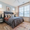 Spacious and well lit bedroom with carpeted floors and a large window 